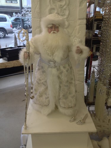 A large Santa all in white with silver Cinderella shoes next to him.  