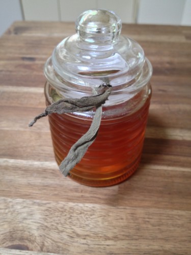 Sage infused honey in a bee hive jar