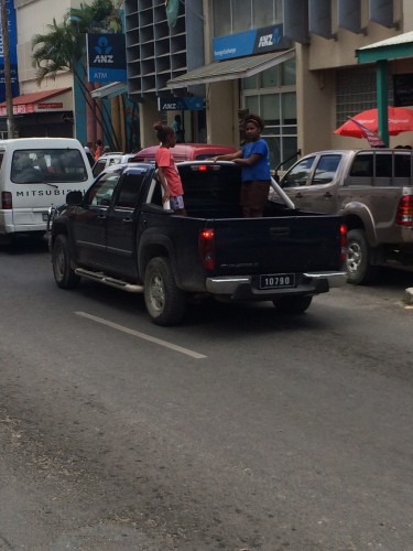 Two young girls just leaning out of a truck on the main street of Port Vila.  