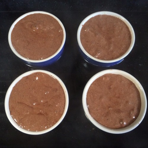 The puddings sitting in a water bath, about to go in the oven