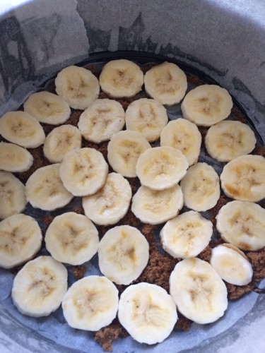 Spreading the sliced bananas across the bottom of the cake tin