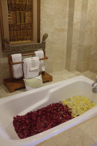 A very welcoming bath tub with rose and frangipani petals. 