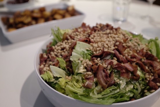 Salad topped with herbs, pine nuts and bacon 